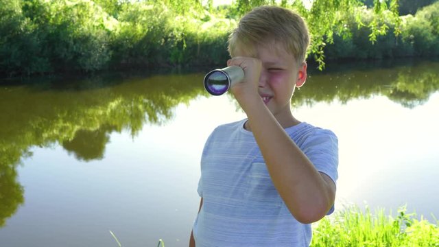 Cute white kid watching through old telescope at something intersting far away in distance. Real time 4k video footage.