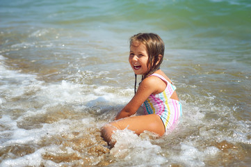 Cheerful little girl enjoys swimming in the sea . Kids activities