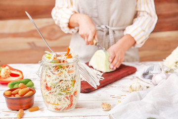 Woman preparing cabbage for fermentation at table, closeup