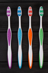 Four colorful toothbrushes on black background. Group of different brushes for cleaning teeth. Dental health concept.