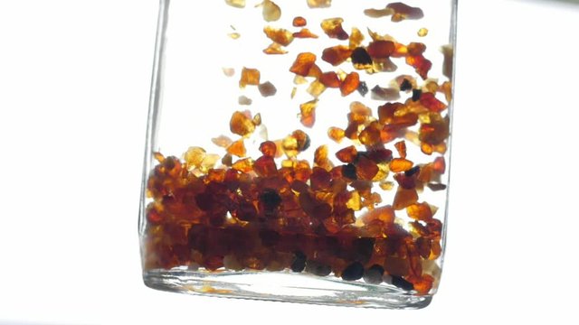 pieces of amber in water falling to the bottom slow motion