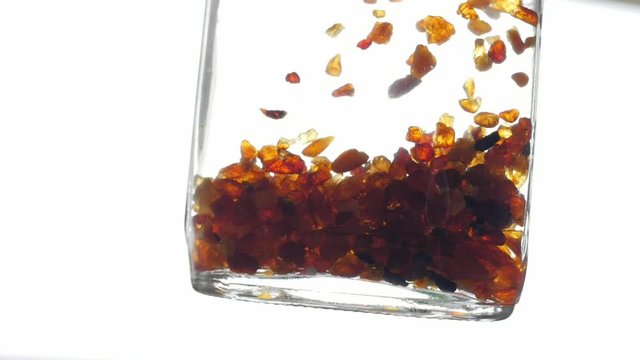 pieces of amber in water falling to the bottom slow motion