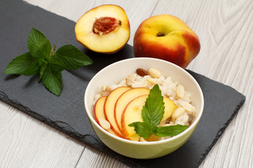 Sorghum salad with nuts and fresh peach on stone board.