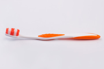 New plastic toothbrush isolated on white background. Orange toothbrush with copy space.