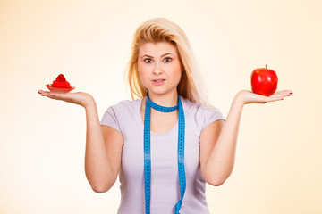 Woman choosing between apple and sweet cupcake