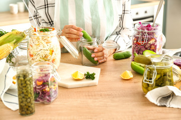Woman preparing cucumbers for fermentation at table, closeup