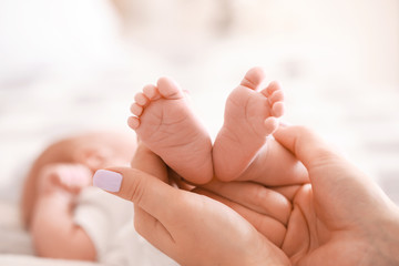 Fototapeta na wymiar Mother's hands with tiny baby legs, closeup
