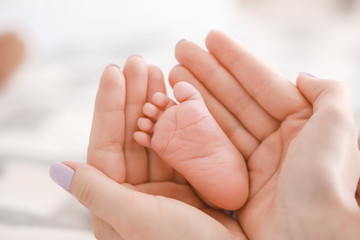 Obraz na płótnie Canvas Mother's hands with tiny baby leg, closeup