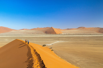 Two hikers walking on the ridge of Dune 45 in the morning light, Namib desert, Namibia
