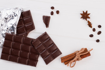 Dark chocolate bars, coffee beans and cinnamon. Chocolate pieces, spices and copy space.