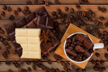 Chocolate pieces and coffee beans. Chunks of chocolate and aromatic coffee beans on wooden table.