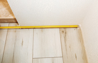 Naklejka na ściany i meble Baseboard installation. Repair works indoors. Renovation in the flat. Tape measure.