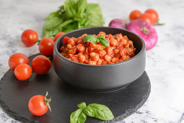 Bowl with tasty chickpea in tomato sauce on table
