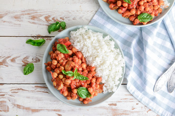 Plate with tasty chickpea in tomato sauce and boiled rice on table
