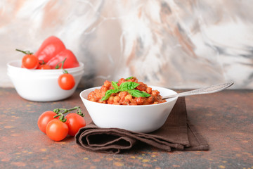 Bowl with tasty chickpea in tomato sauce on table