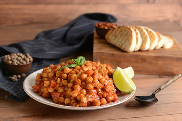 Plate with tasty chickpea in tomato sauce on table