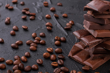 Stack of chocolate bars and coffee beans background. Chocolate and coffee beans on black concrete background.