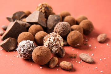 Tasty sweet truffles and chocolate on color background