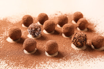 Tasty sweet truffles and cacao powder on light background