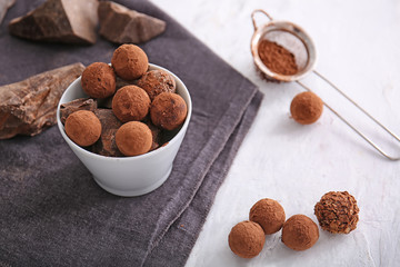 Bowl with tasty sweet truffles on light table