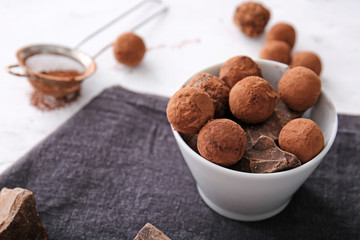 Tasty sweet truffles in bowl on table