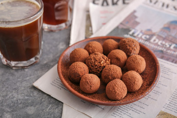 Plate with tasty sweet truffles and drink on table