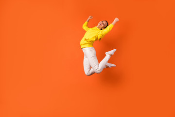 Full size photo of cheerful millennial raise fist smiling jumping wearing white pants trousers...