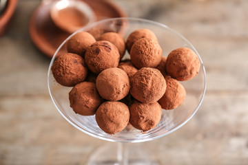 Glass with tasty sweet truffles on table, closeup