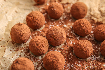 Tasty sweet truffles on parchment, closeup