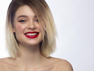 Close-up portrait of a beautiful woman smiling at the camera. Short hair and evening makeup. Pink lips and eyeliner. Happy smile with white teeth. Spa and cosmetology, dentistry