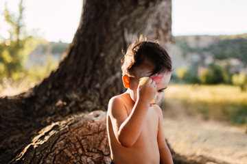 Kid painting himself of dracula to halloween on the forest
