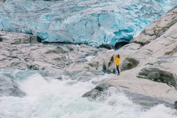 A girl stands on the background of the Nygardsbreen glacier and the glacial river in Norway.Adventure Lifestyle concept vacations outdoor Nigardsbreen glacier,Jostedalsbreen National Park