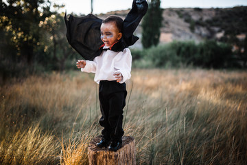 Kid smiling costumed of dracula to halloween on the forest