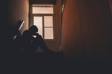 Silhouette Sad young man sitting at the stairs in the dark, Depression and anxiety disorder...