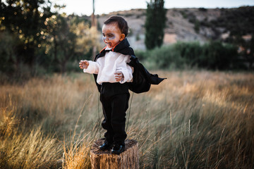 Kid smiling costumed of dracula to halloween on the forest