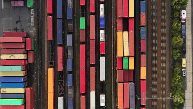 Flying above industrial railroad station with cargo trains and freight containers. Railroads and shipping container trains.