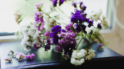 A bouquet of dried violet, pink and white wildflowers lying on the book. Bright flowers lit by sunlight. Soft selective focus, macro flowers. Photo background