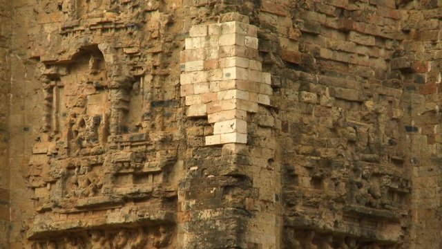 A steady closeup shot of one of the corners of the Khmer ruins of Sambor Prei Kuk showing a nearly destroyed Buddha figure on its wall exterior..