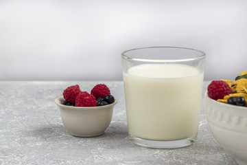 Healthy tasty breakfast: bowl with corn flakes and berries and glass of milk.