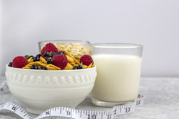 Healthy tasty breakfast with corn flakes and berries, a glass of milk and a glass of oatmeal.