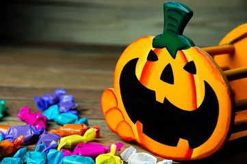 Foto op Plexiglas Happy Halloween Jack O Lantern halloween pumpkin basket and Trick or Treat candies on wooden background. © Jack Tamrong