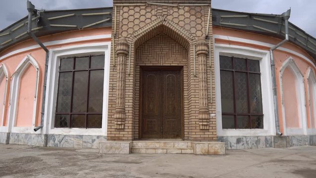 Qurghonteppa Bokhtar Teppa Modern History Museum Monument Main Gate Entrance Frontal View with Waving Tajikistan Flag on a Cloudy Rainy Day