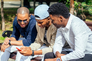 a group of three fashionable well-dressed cool African American guys students communicating on the street - obrazy, fototapety, plakaty