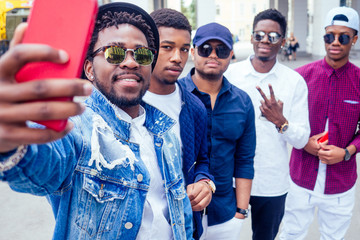 a group of five fashionable cool African American guys students communicating on the street looking...