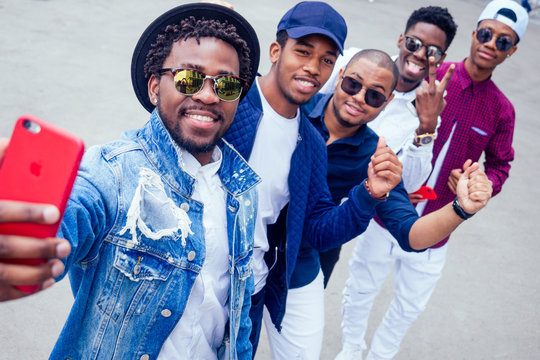 a group of five fashionable cool African American guys students communicating on the street looking at smartphone take pictures selfie on phone in street
