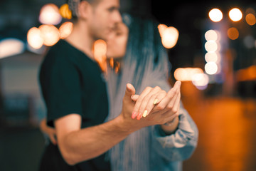 Young couple holding hands at night dancing with love - Powered by Adobe