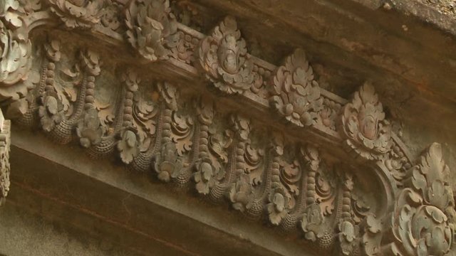 A closeup shot with a panning view of the lintel of the Khmer ruins of Sambor Prei Kuk showing the intricate carved detailing of the horizontal block made of stone that decorates the top portion of