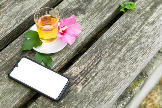 Mallow tea with smartphone on old wooden background