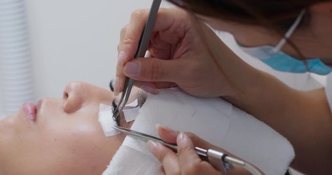 Young woman undergoing procedure of eyelashes extension