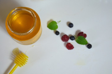 Healthy breakfast ingredients. fresh fruit, berries mint, a jar of honey with a spoon for honey on a white background. Top view, copy space